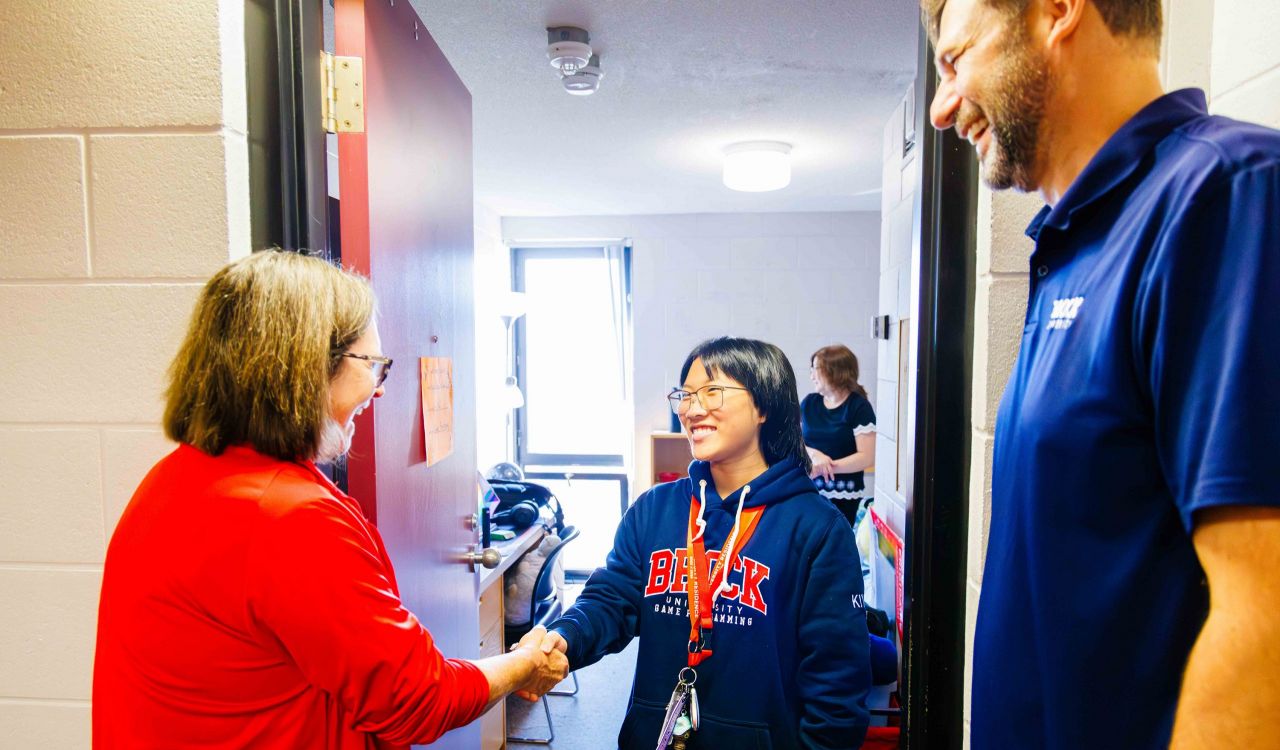 Three people chat while standing a doorway.