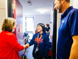 Three people chat while standing a doorway.