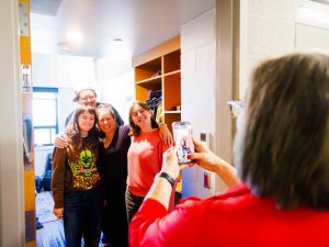 A woman takes a photo of a group of people on her cellphone.