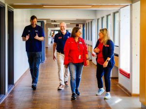 Four people walk down a hall.