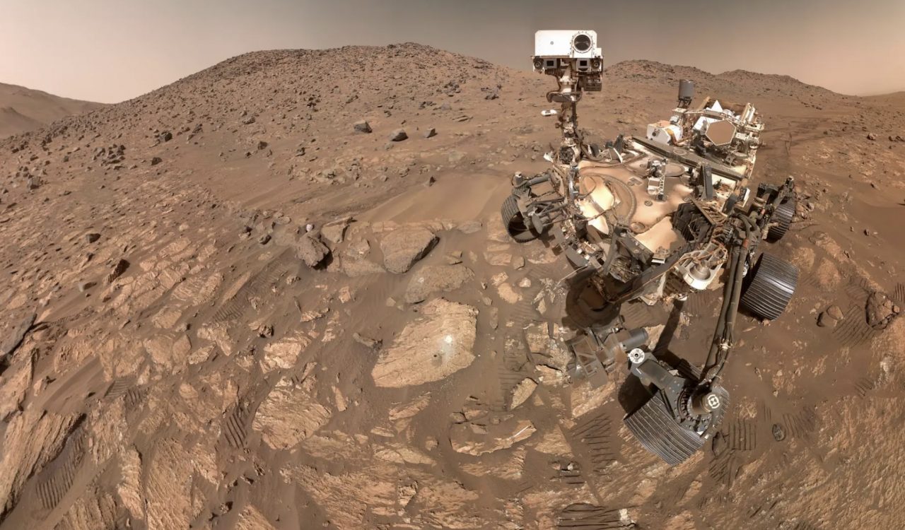 The dry, dusty, rocky surface of Mars is shown alongside the Perseverance rover, a robot able to terrain the Red Planet.