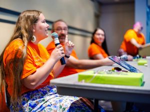 Group of people sit at a table and hold microphones.