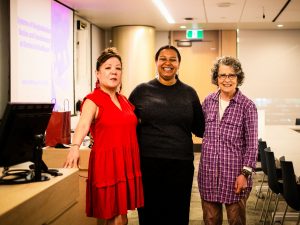Three women stand side-by-side in a classroom.