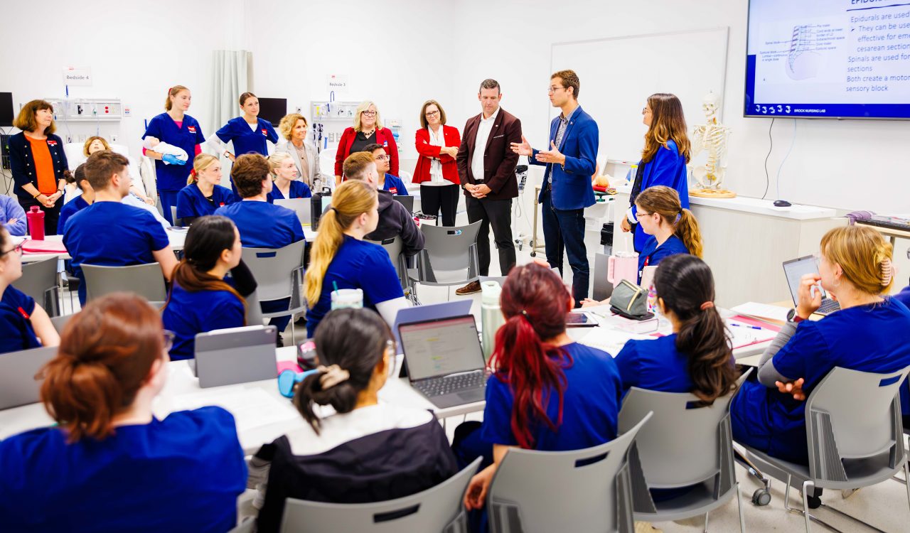 A man speaks to a group of nursing students.
