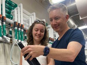 A man and a woman look at a wine bottle.