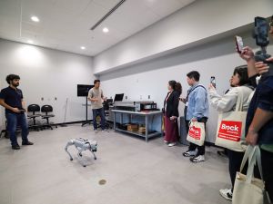 A group of people watch a robot demonstration in a lab.