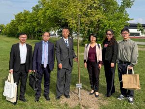 A group of people pose beside a small tree.
