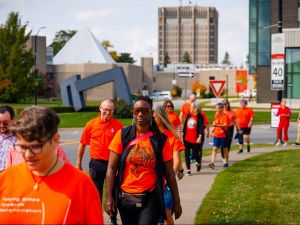 Participants wearing orange shirts walk through Brock University’s campus.