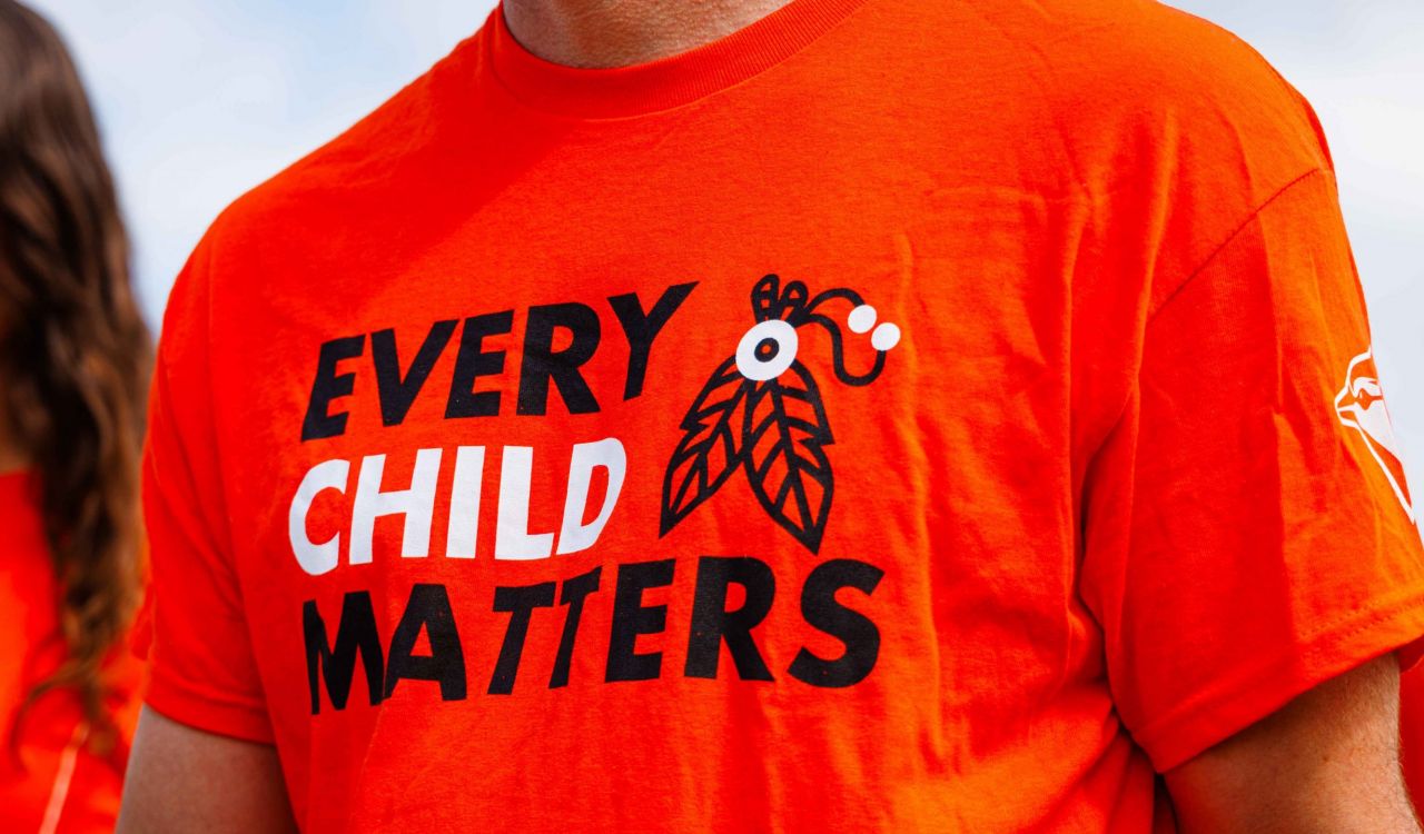 Close-up of a man wearing an orange "Every Child Matters" shirt.