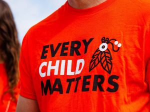 Close-up of a man wearing an orange "Every Child Matters" shirt.