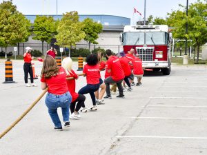 A group of people in red shirts pull a fire truck.