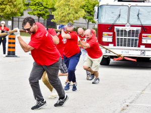 A group of people in red shirts pull a fire truck.