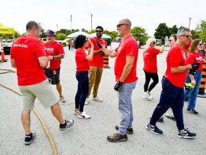 A group of people in red shirts chat and high five in a parking lot.