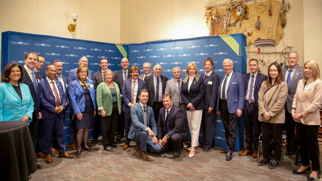 A large group of people in business attire pose in front of a blue backdrop.
