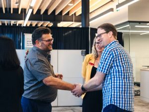 Two people shake hands at a networking event.