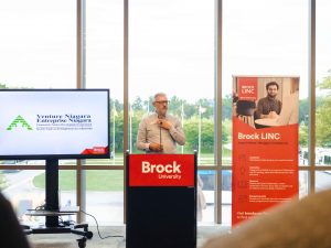 A man speaks from a podium at a networking event.