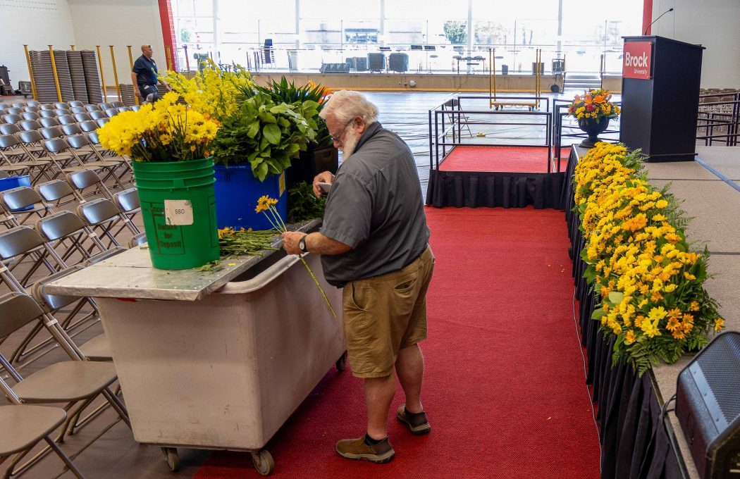 A man arranges flowers in a university gymnasium.