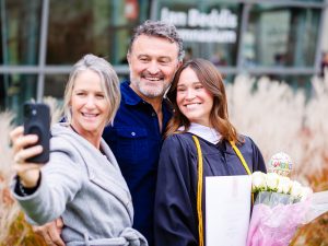 A graduate takes a selfie with her parents outside the convocation venue.