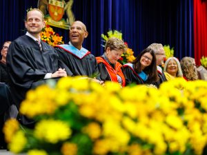Faculty members smile and laugh together during the ceremony.