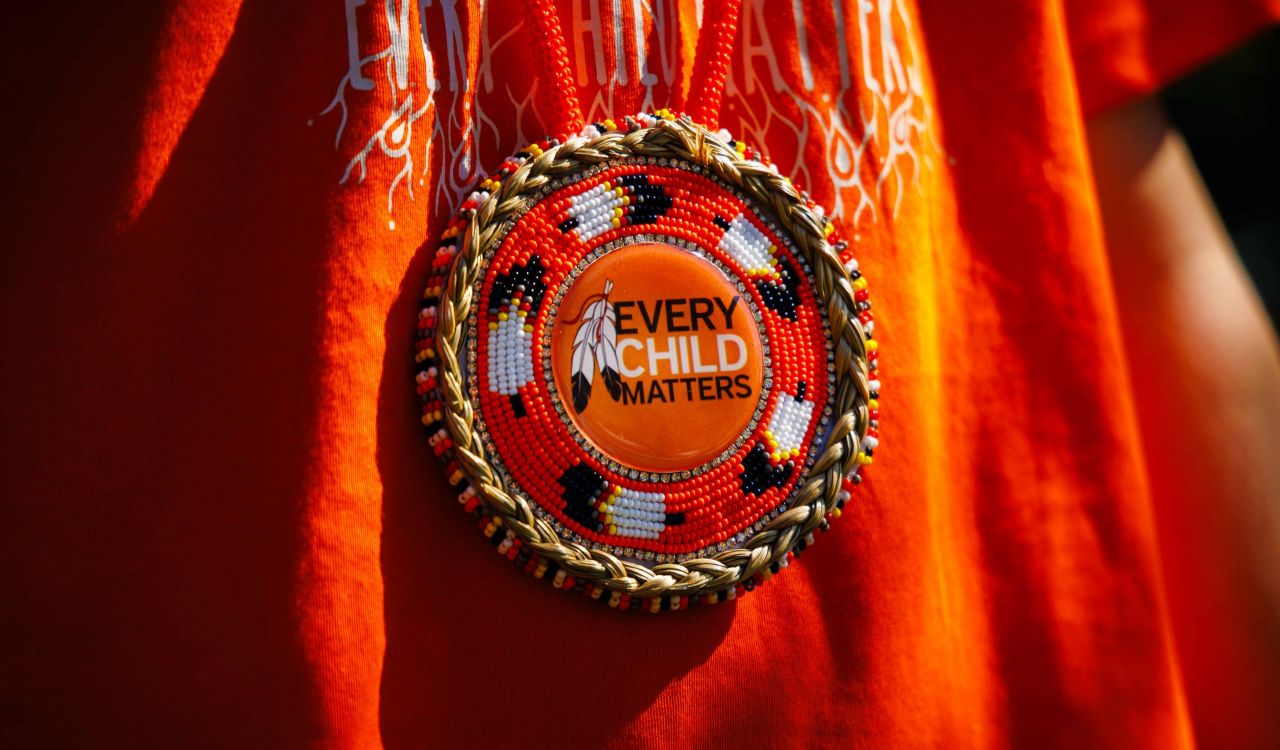 Beaded medal worn over an orange shirt.