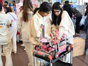 Two teenage girls work on a robot at a robotics competition.