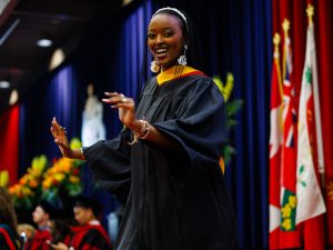 Woman wearing academic regalia dances on stage during Brock University's 118th Convocation.