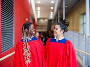 Two women wearing academic regalia smile at one another during Brock University's 118th Convocation.