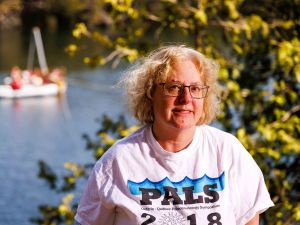 A woman stands in front of a lake. 
