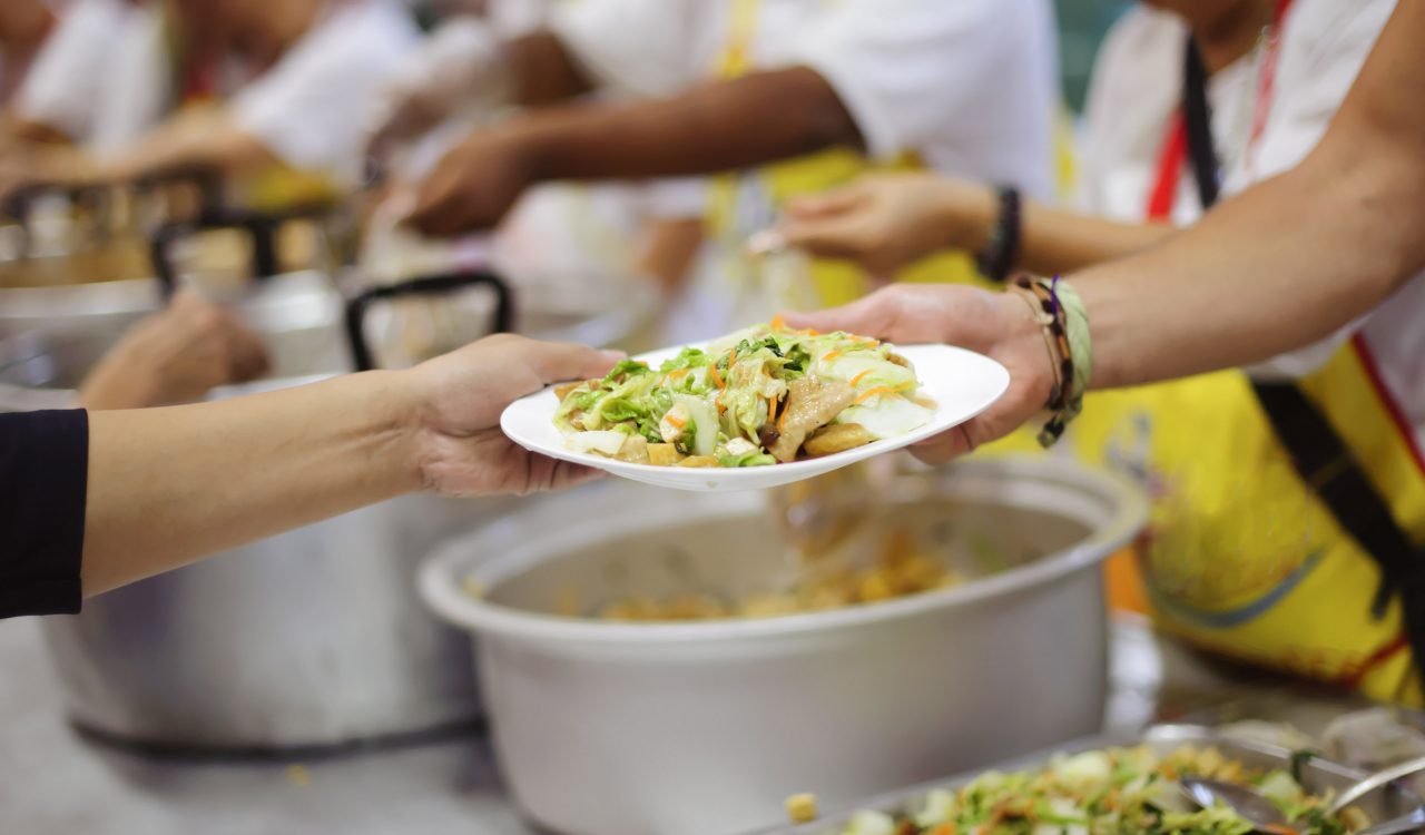Close up of volunteer handing a meal to someone meal.