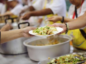 Close up of volunteer handing a meal to someone meal.