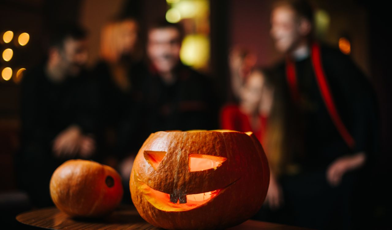 Close-up of a carved pumpkin with out-of-focus people in costumes in the background.
