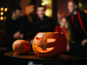 Close-up of a carved pumpkin with out-of-focus people in costumes in the background.