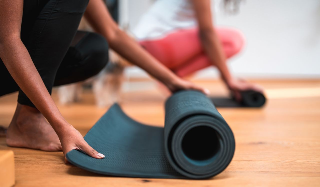 Close-up of two people unrolling yoga mats.