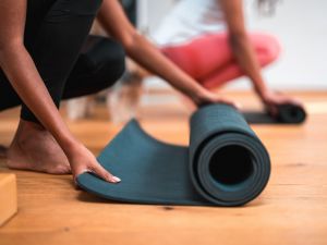Close-up of two people unrolling yoga mats.
