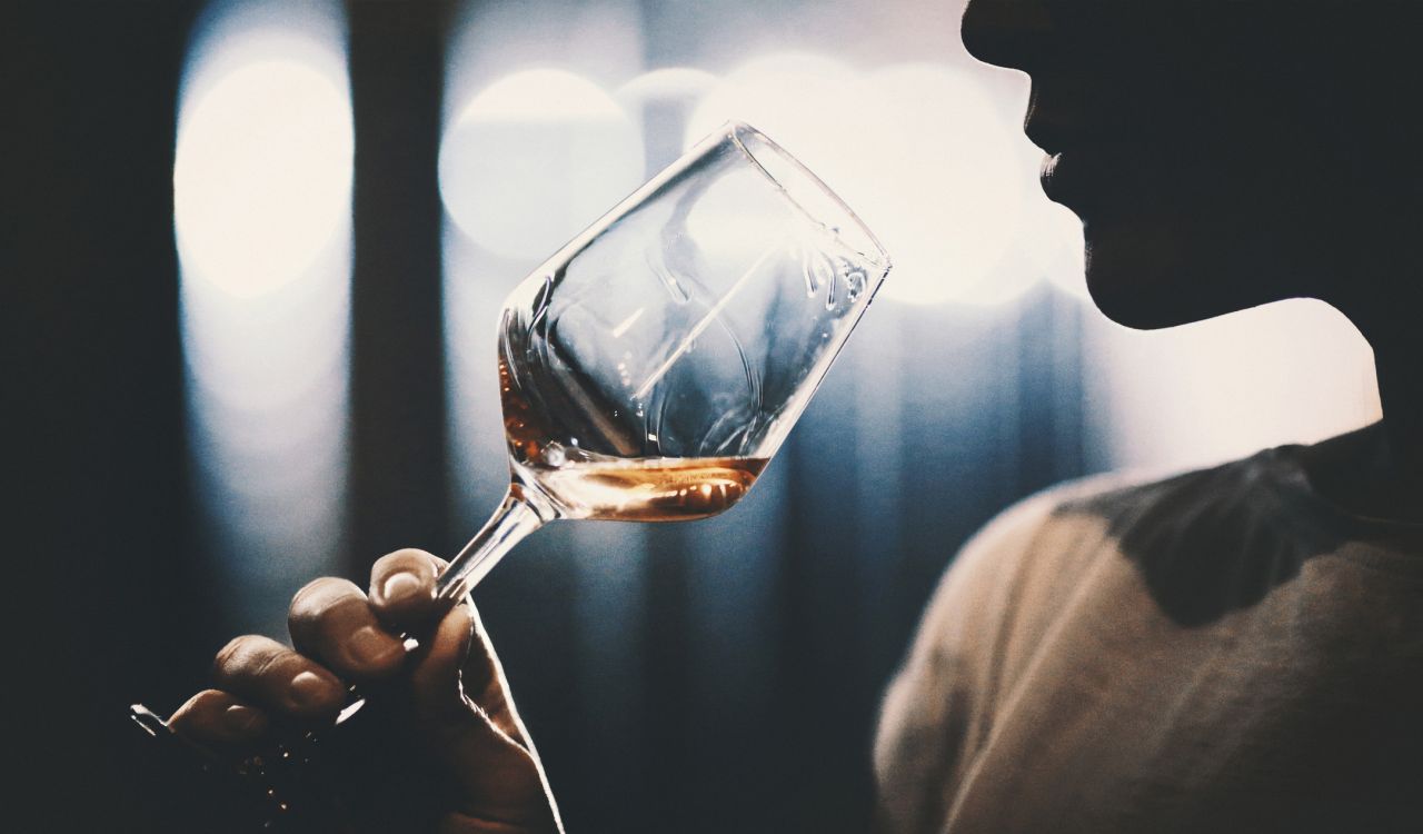 Close-up view of a person drinking a glass of wine.