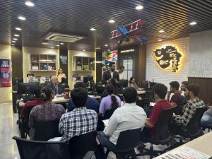A group of people sit listening to a speaker in a meeting room.