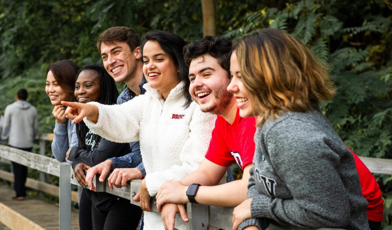 A group of university students pose for a photo on a bridge.