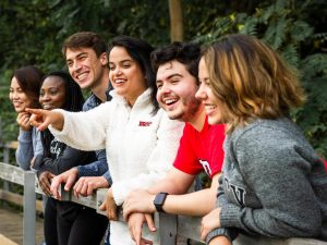 A group of university students pose for a photo on a bridge.