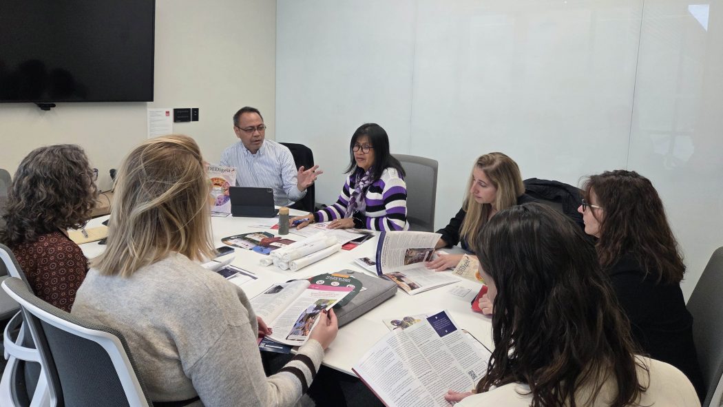 A group of people sit around a table during a meeting.