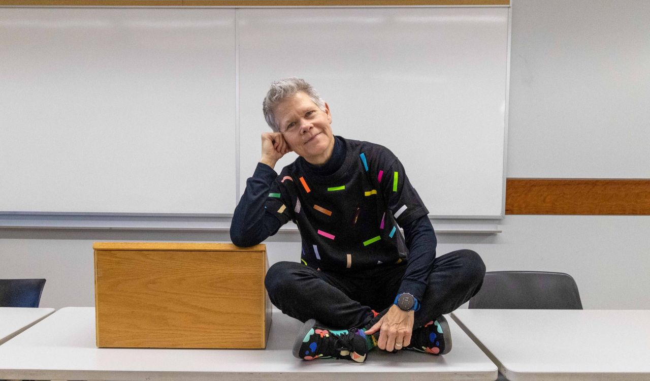 A person sits on a table in a university classroom.