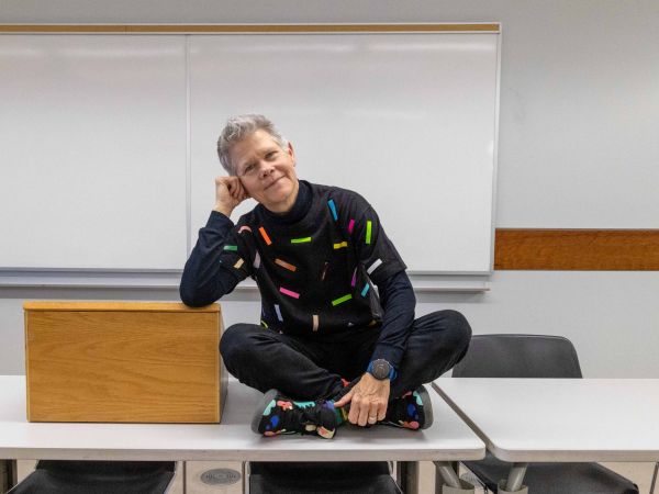 A person sits on a table in a university classroom.