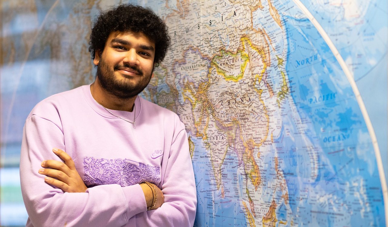 Man stands in front of a map on the wall.