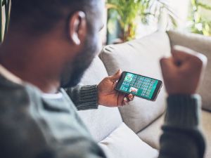 Man cheers while making a bet on a cell phone.