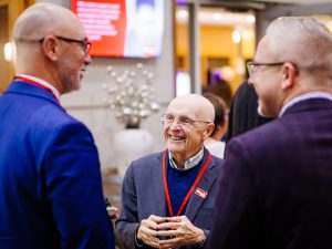 Three men talk together and smile during the reception.