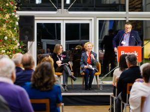A panel speaks on stage beside a decorated Christmas tree at Brock University.