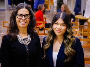 Two women pose for a photo inside the event space.