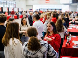 A Brock representative talks with prospective students at a crowded information fair.