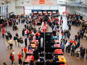 Overhead view of a busy information fair with students, families, and Brock staff engaging at booths.
