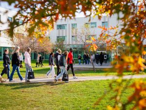 Campus tour group walks through Brock University’s grounds framed by autumn leaves.
