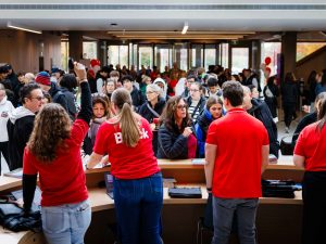 Brock staff in red shirts greet and assist visitors at a busy check-in area.